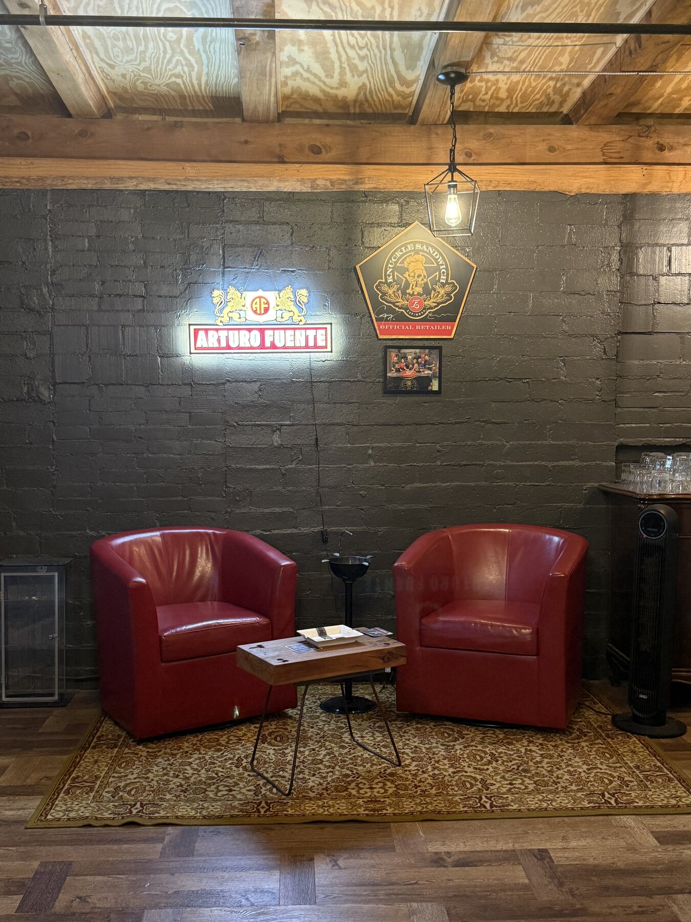 Two red club chairs under a lantern against the painted brick wall